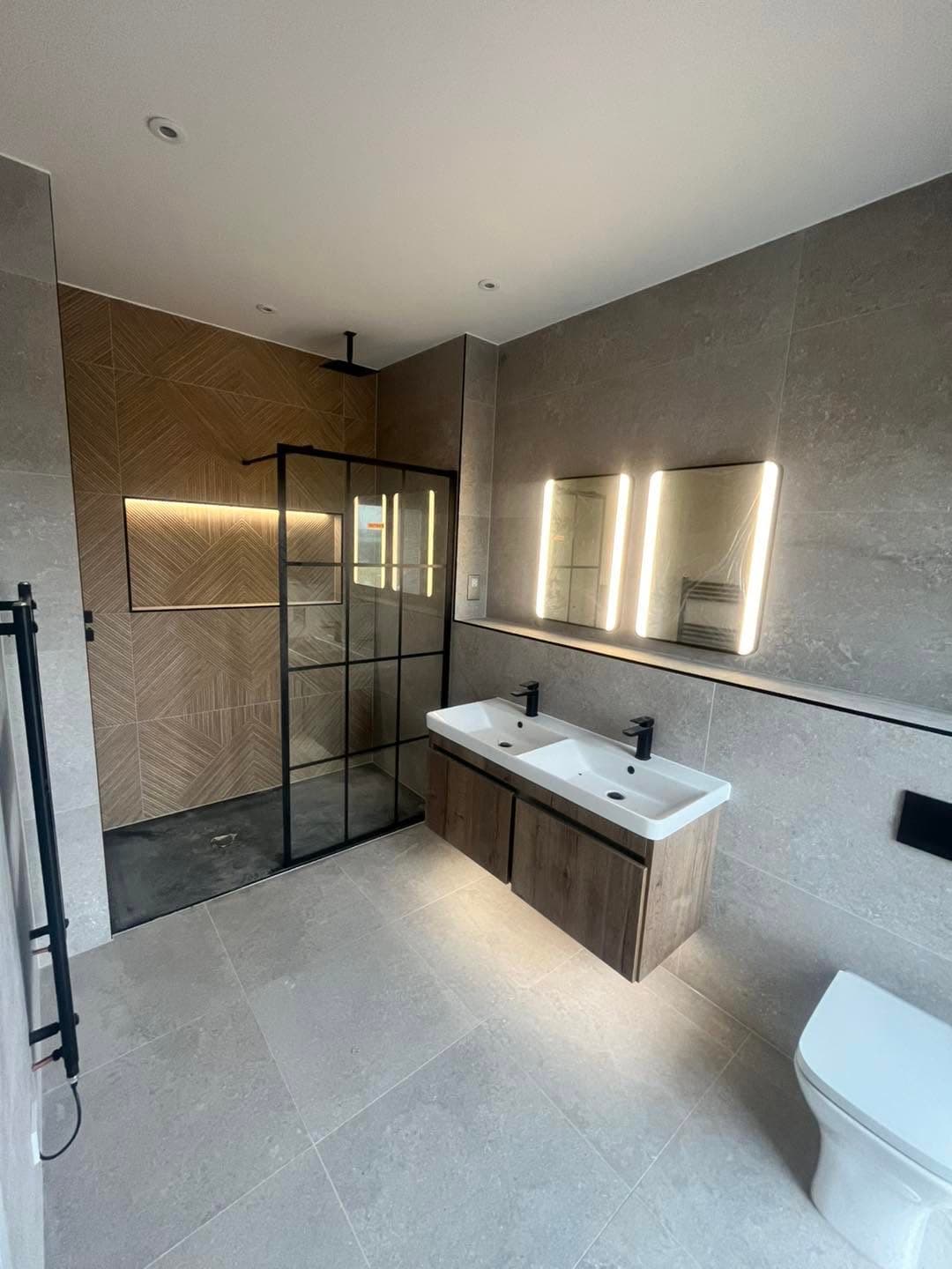 High-end bathroom refit with backlit mirrors, recessed niche lighting and a walk-in shower, wired by Gunning Electrical Services