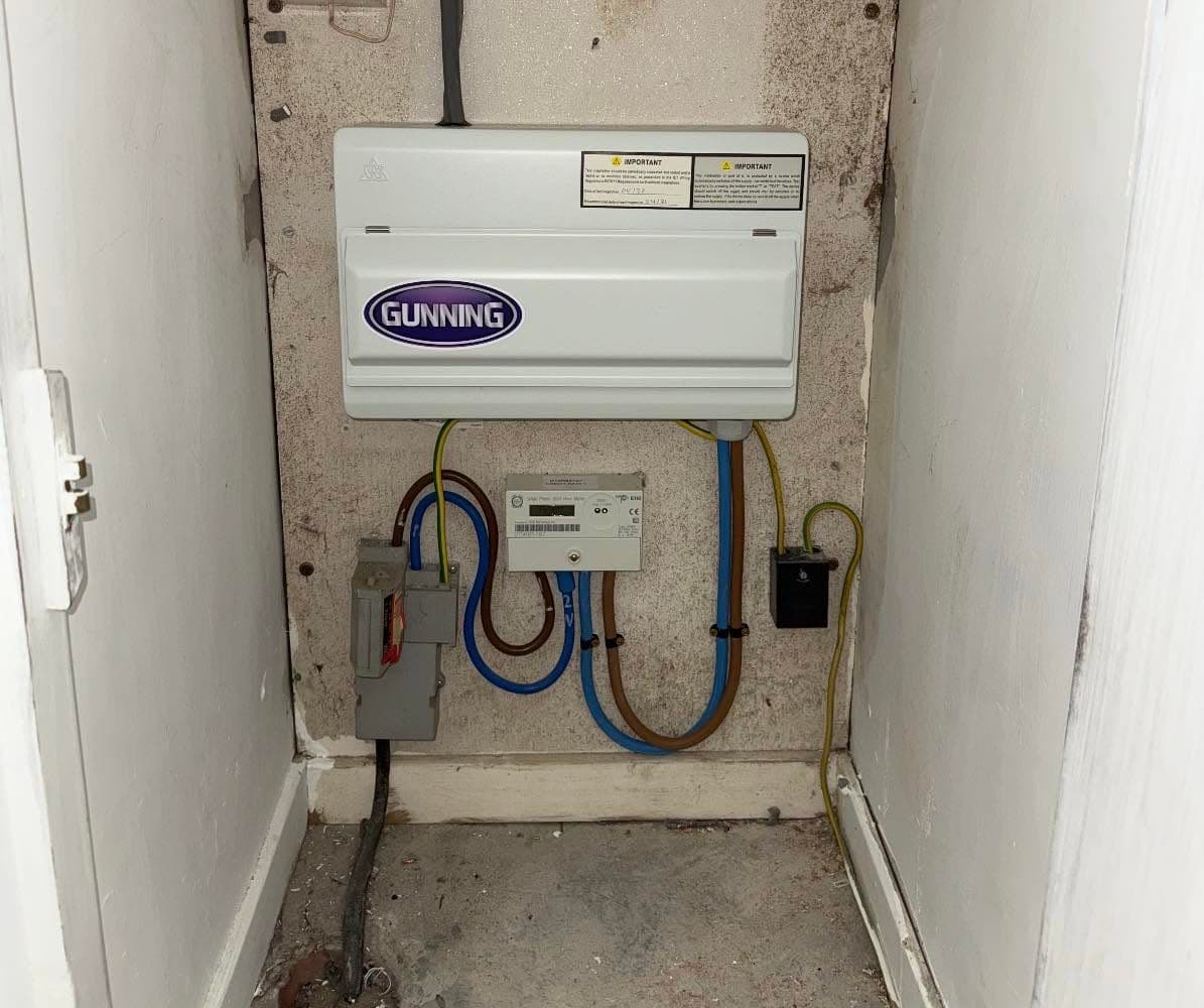 New Gunning-branded consumer unit with neatly clipped meter tails in a meter cupboard